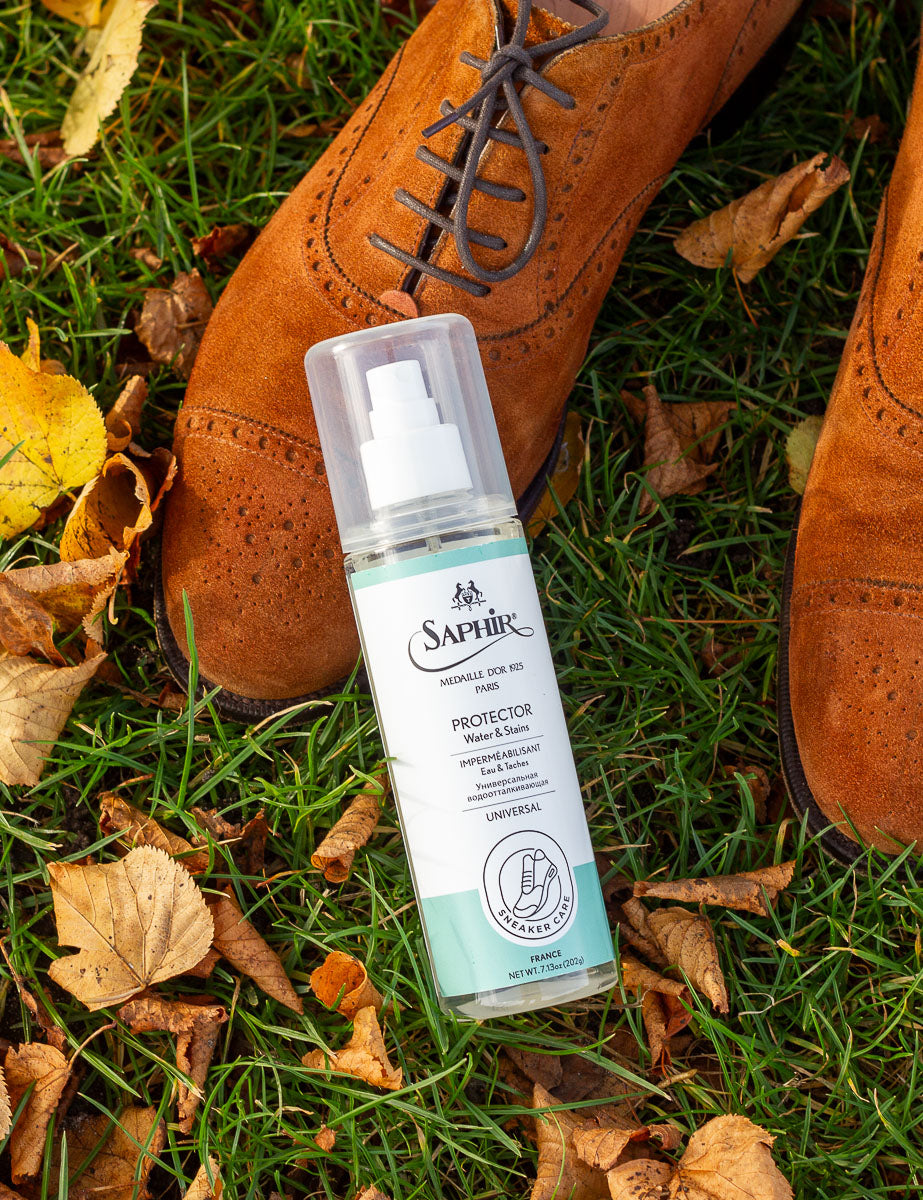 Bottle of Saphir natural protector spray on grass with brown shoes